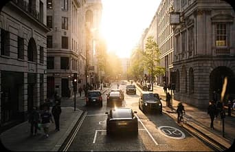A sunlit London street lined with parked cars