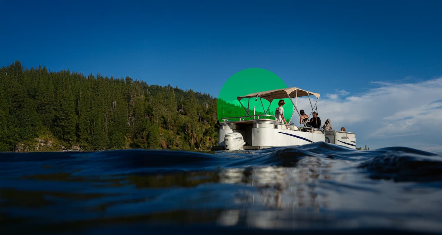Pickup truck towing travel trailer on paved highway with yellow center lines through forested area