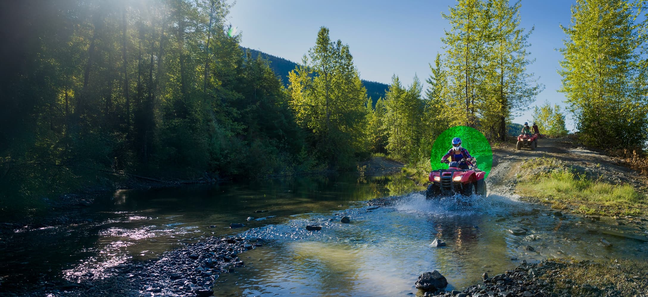 Person riding on atv trough a water in the forest