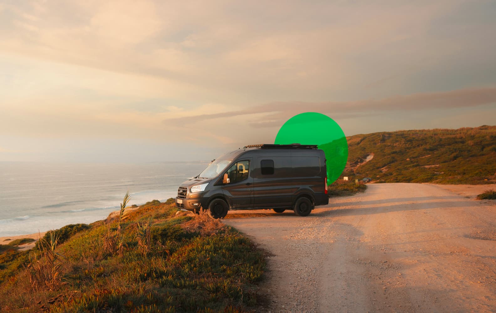 Black pickup truck with camper attachment positioned on sandy desert terrain with red rock formations in background