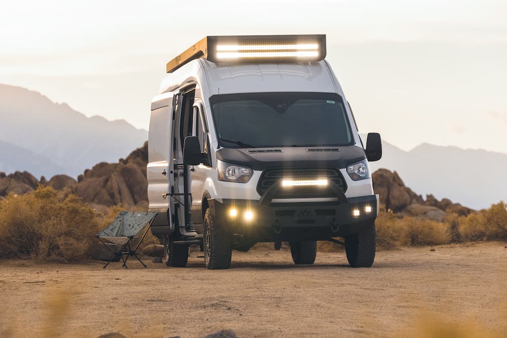 RV campsite setup beside pristine lake with awning extended for outdoor living