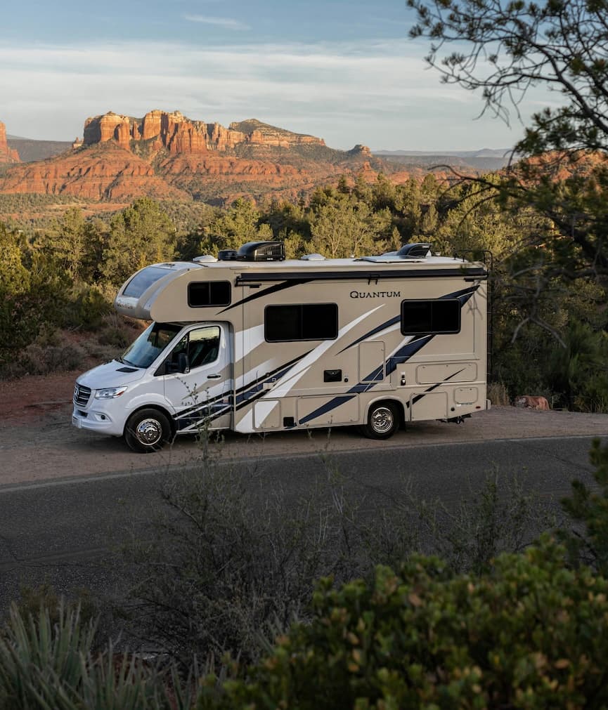 Pickup truck towing travel trailer on paved highway with yellow center lines through forested area
