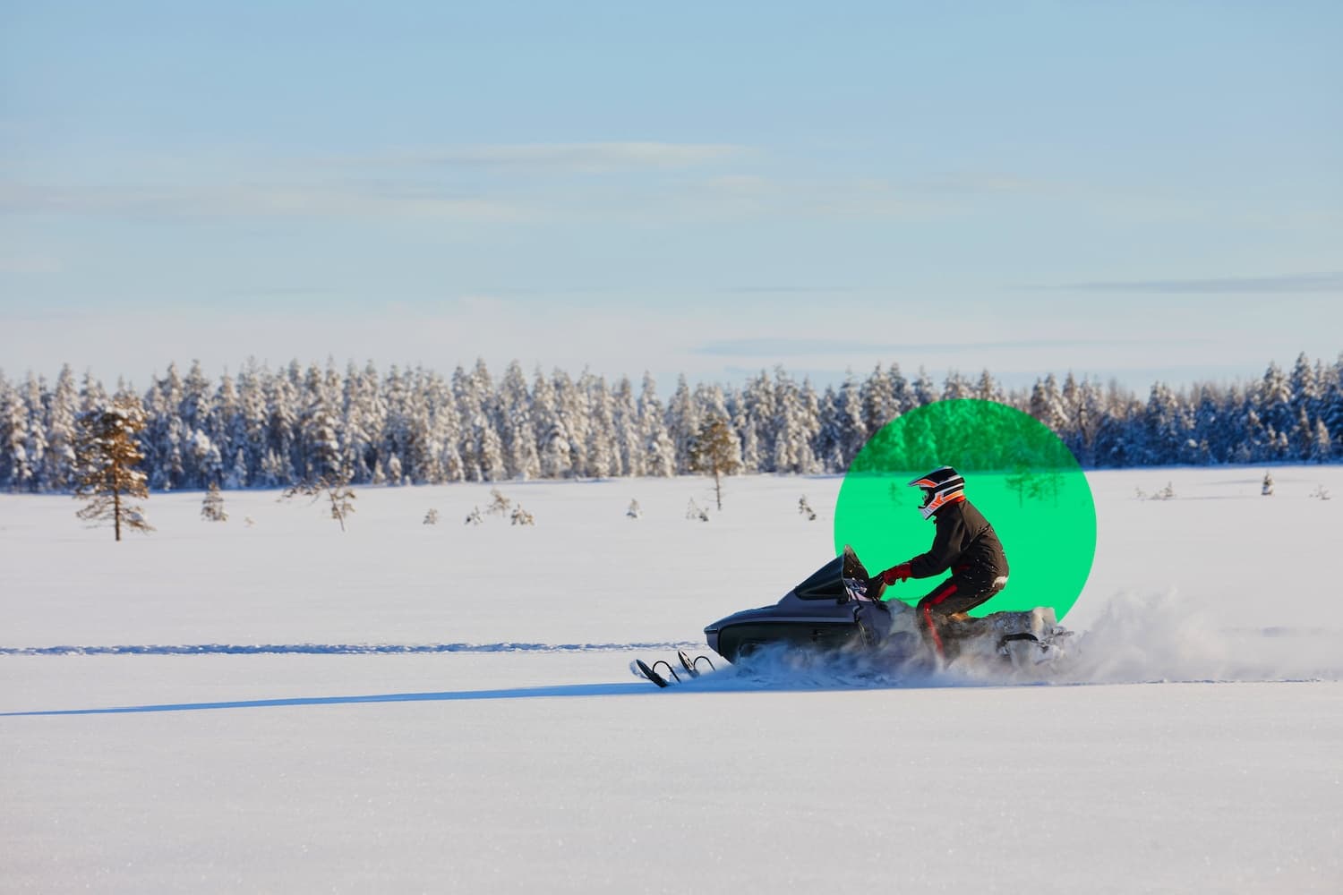 Person on a snowmobile riding through a snowy landscape