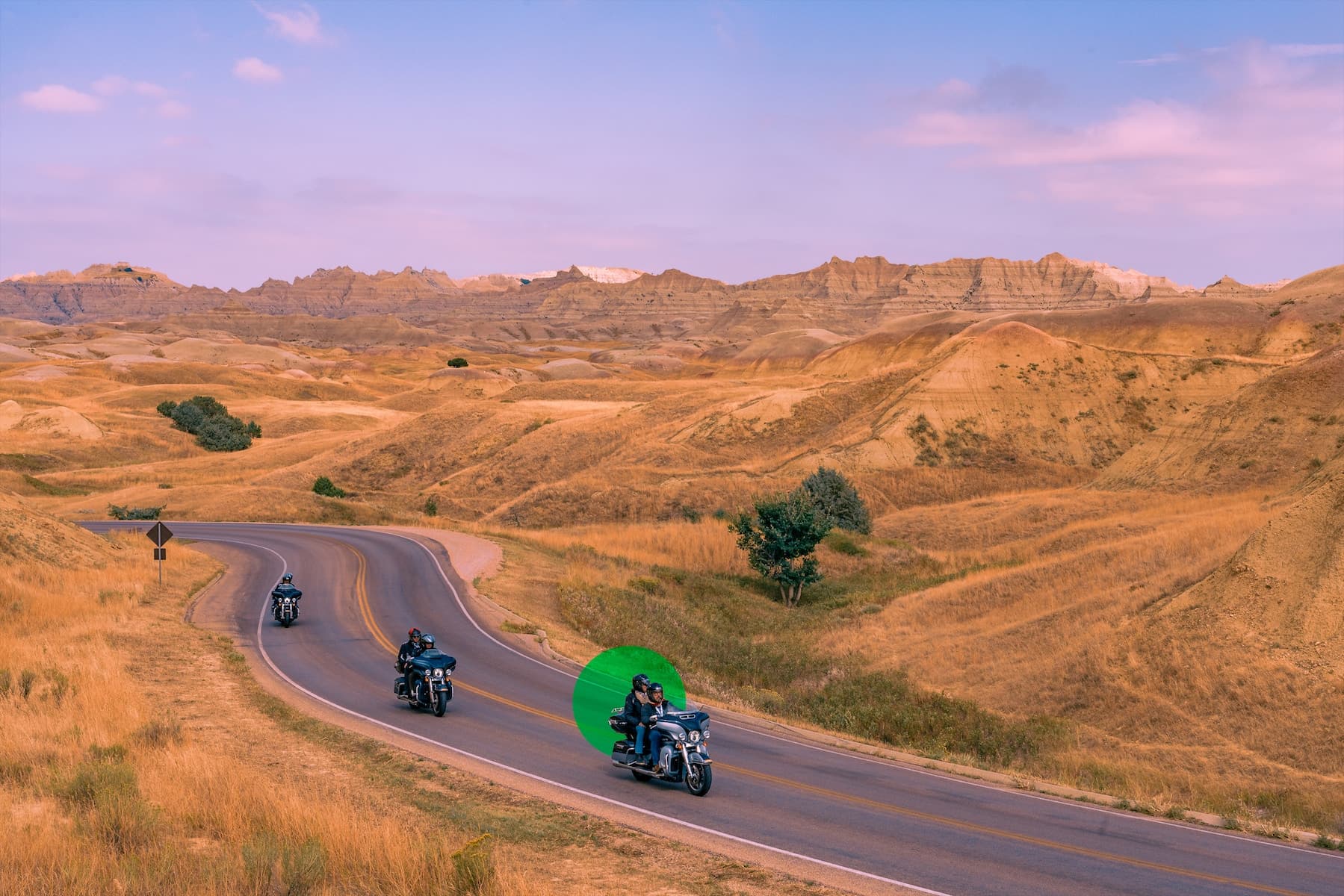 Group of motorcyclists riding on a scenic road with mountains in the background