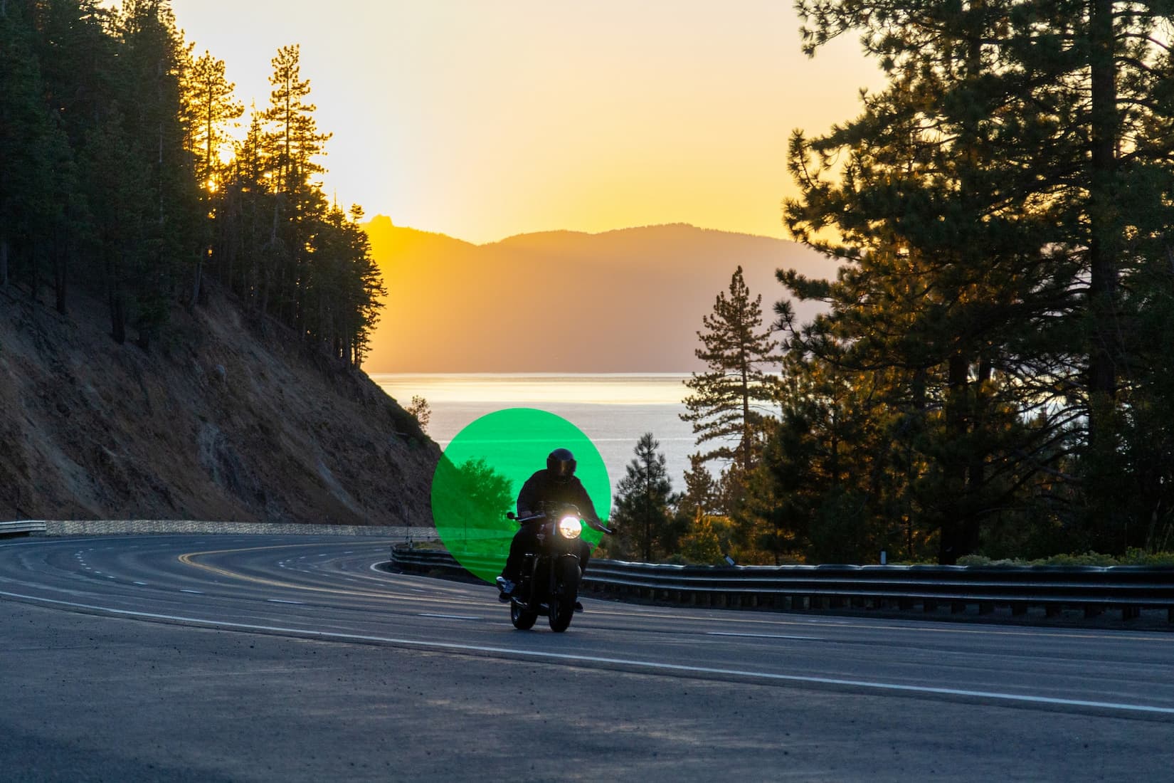 Person riding on a motorcycle at sunset on a winding road
