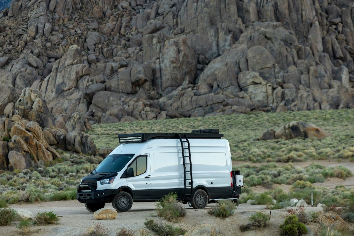Travel trailer RV parked at lakeside campsite with mountain views