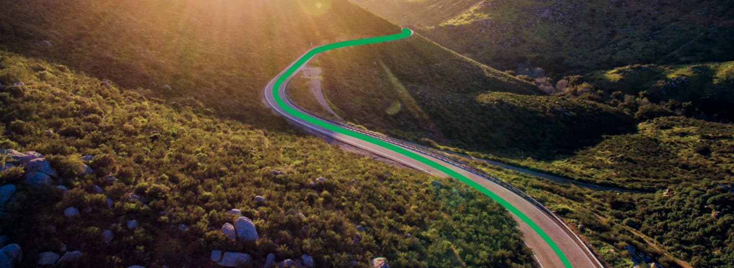Winding mountain highway curves through rolling green hills at golden sunset, perfect scenic route for RV adventures