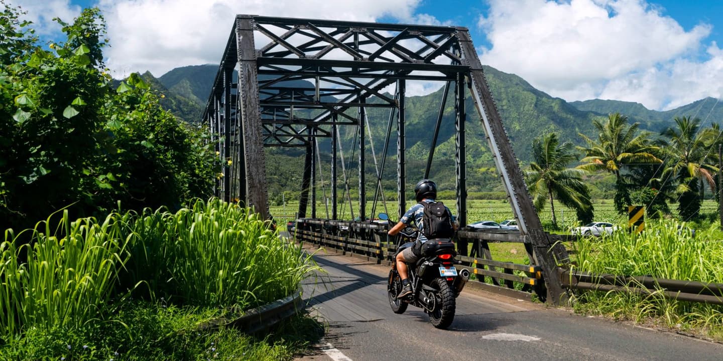 Motorcycle rider crossing a bridge on a scenic road in Hawaii
