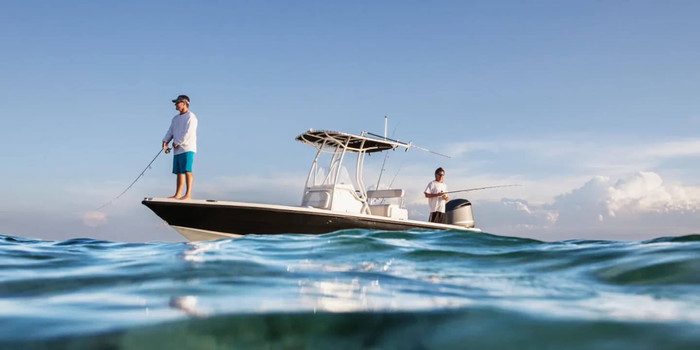 Two people fishing from a center-console boat in open ocean waters