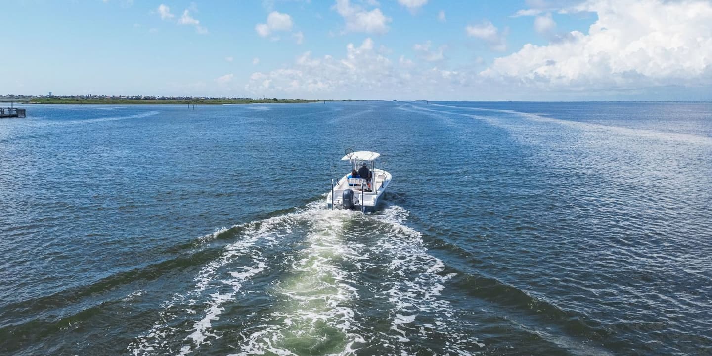 A small motorboat leaves a white wake as it travels across the water, a common sight for those with Texas boat insurance.