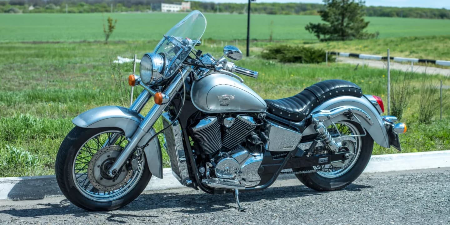 Silver Honda Shadow cruiser motorcycle parked beside a grassy field