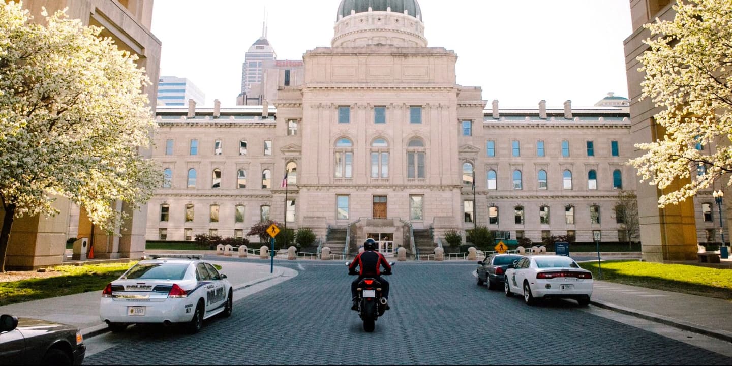 Motorcycle rider traveling past a historic building in Indiana