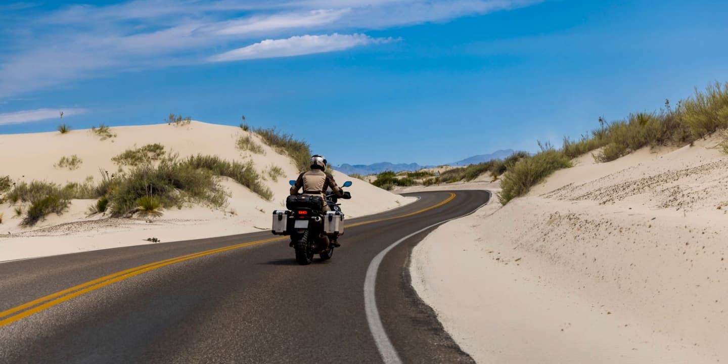 Motorcycle rider traveling along a coastal-style scenic road in New Mexico