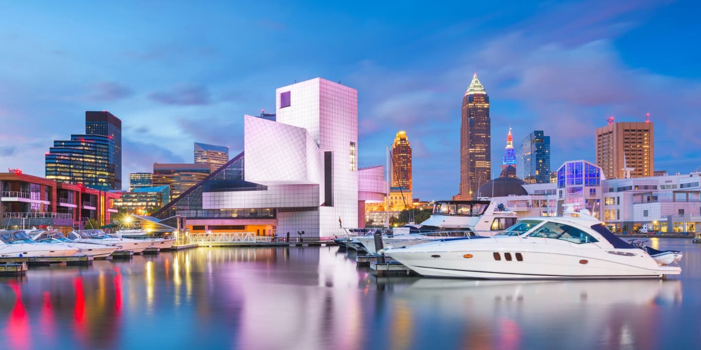 The Rock and Roll Hall of Fame and Cleveland skyline at twilight, viewed from a marina where yachts covered by Ohio boat insurance are docked in the foreground.