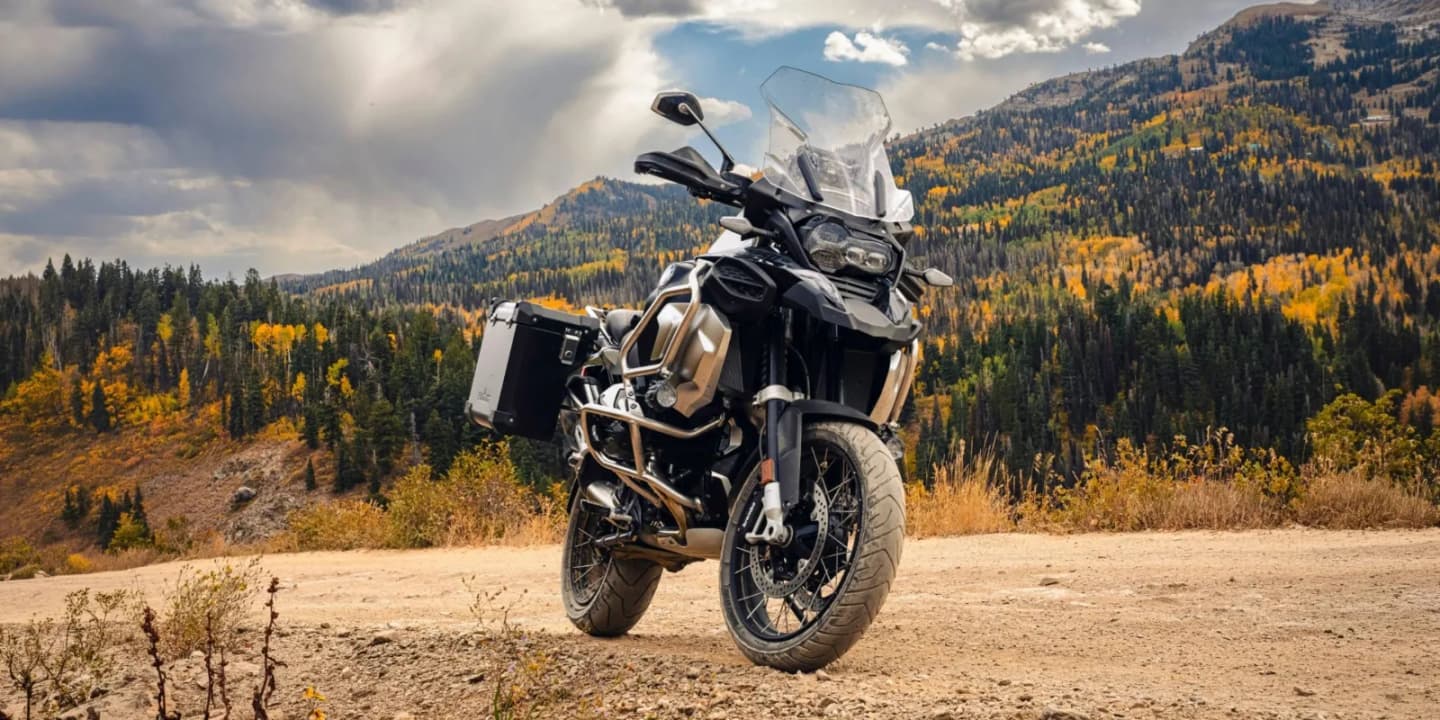 Adventure motorcycle with windshield and side panniers parked on a mountain trail in autumn
