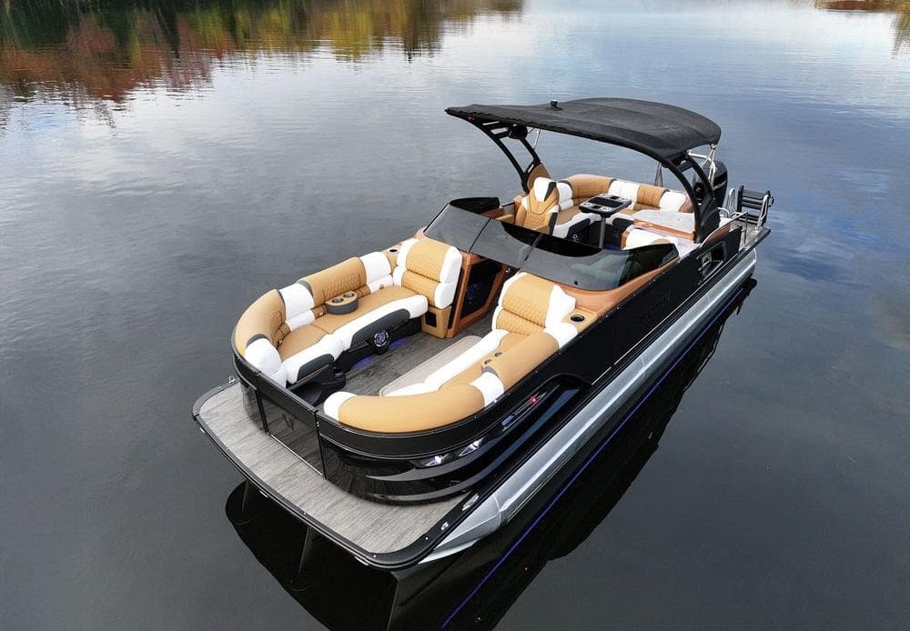 Pontoon boat with a bimini top tied up at a wooden dock on a lake