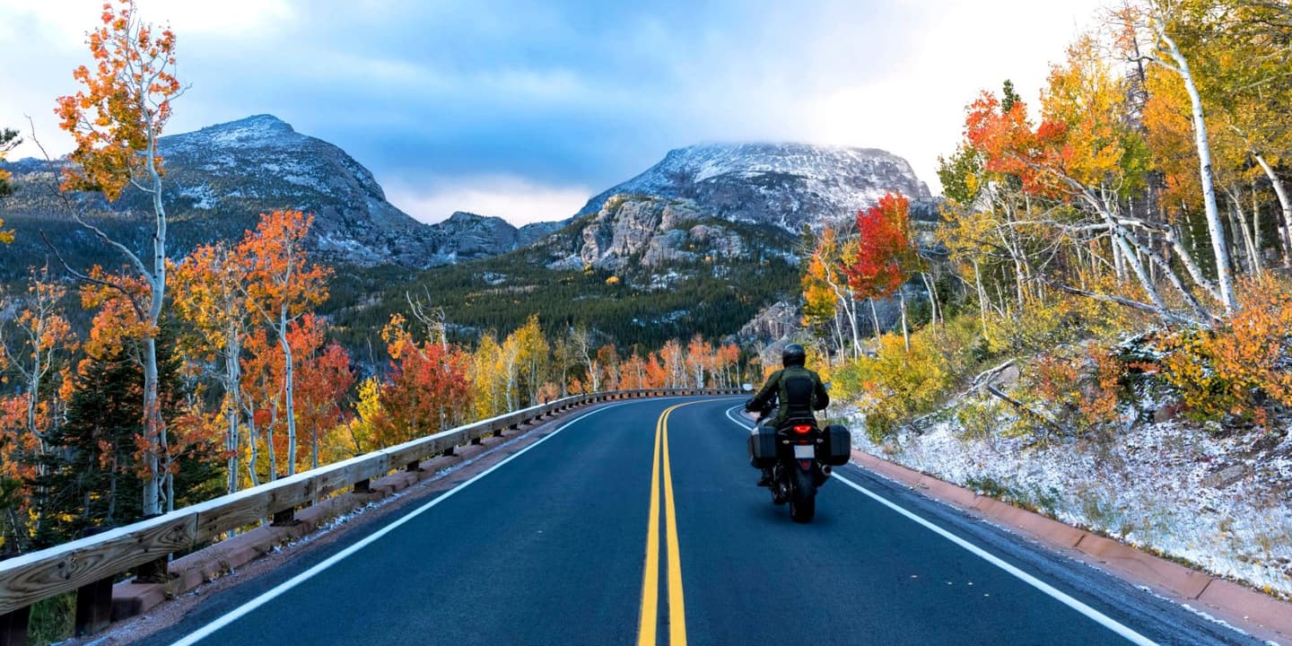 Motorcycle rider traveling along a scenic mountain road in Colorado