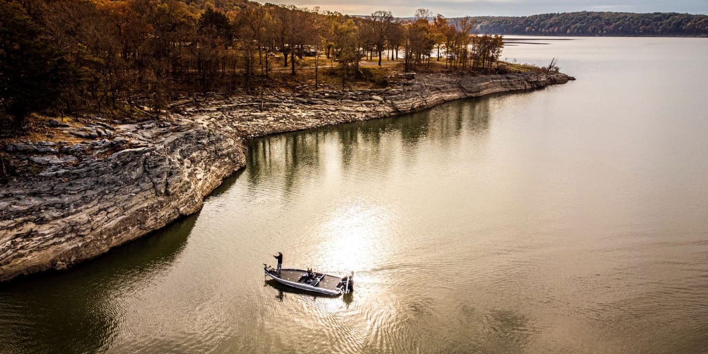 An aerial view of a fishing boat on a lake next to a rocky shoreline in Oklahoma